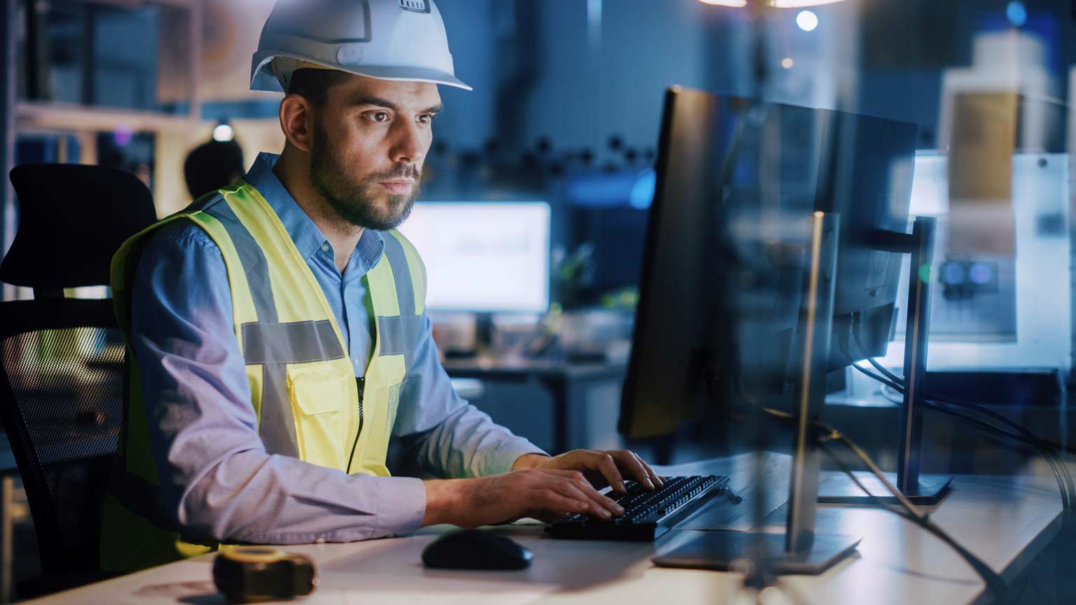 Electronics Design Factory Portrait of Handsome Male Engineer Wearing Safety Vest Working on Computer, Developing Industrial